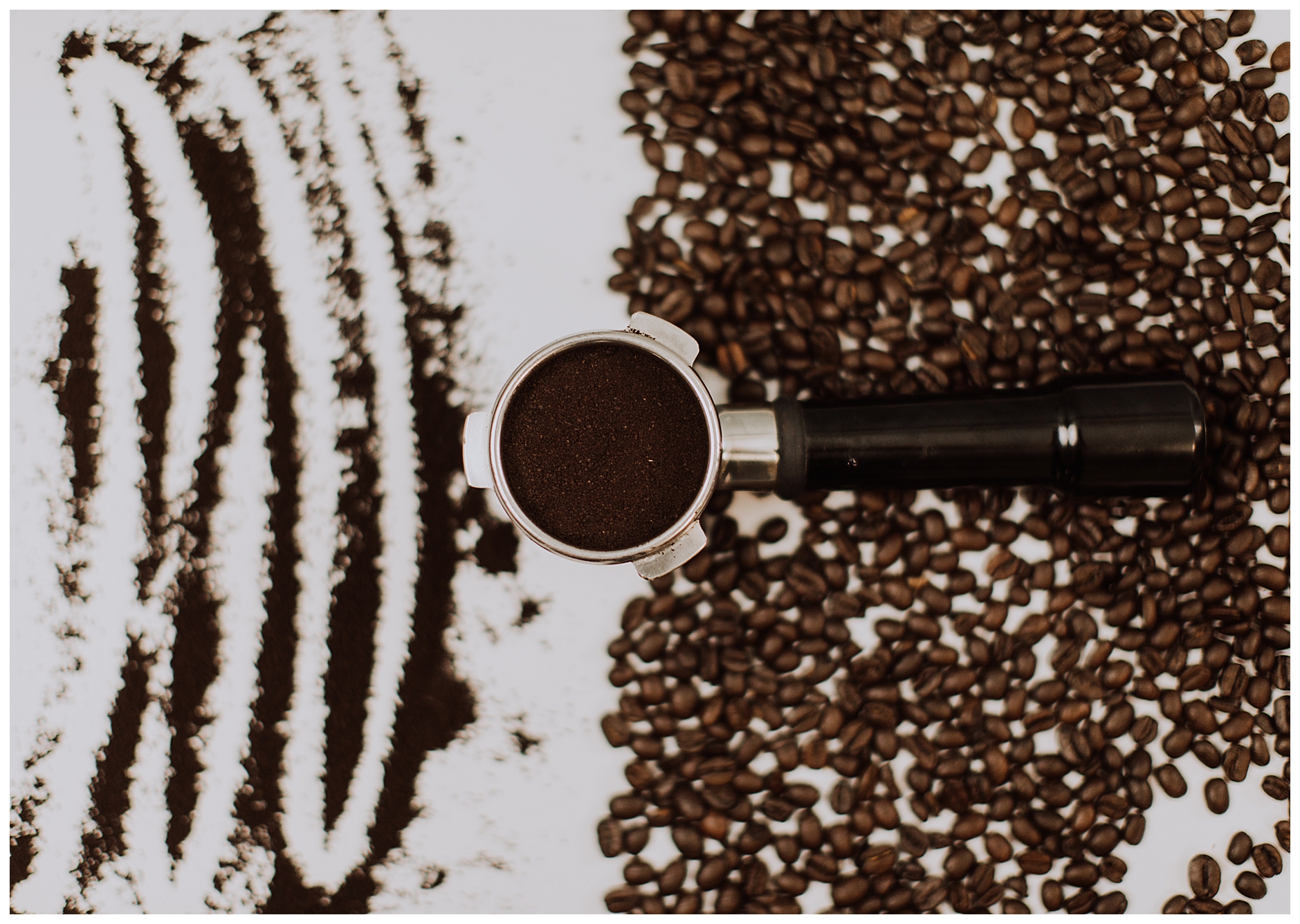 coffee beans and coffee grounds with a port-a filter on a brown table