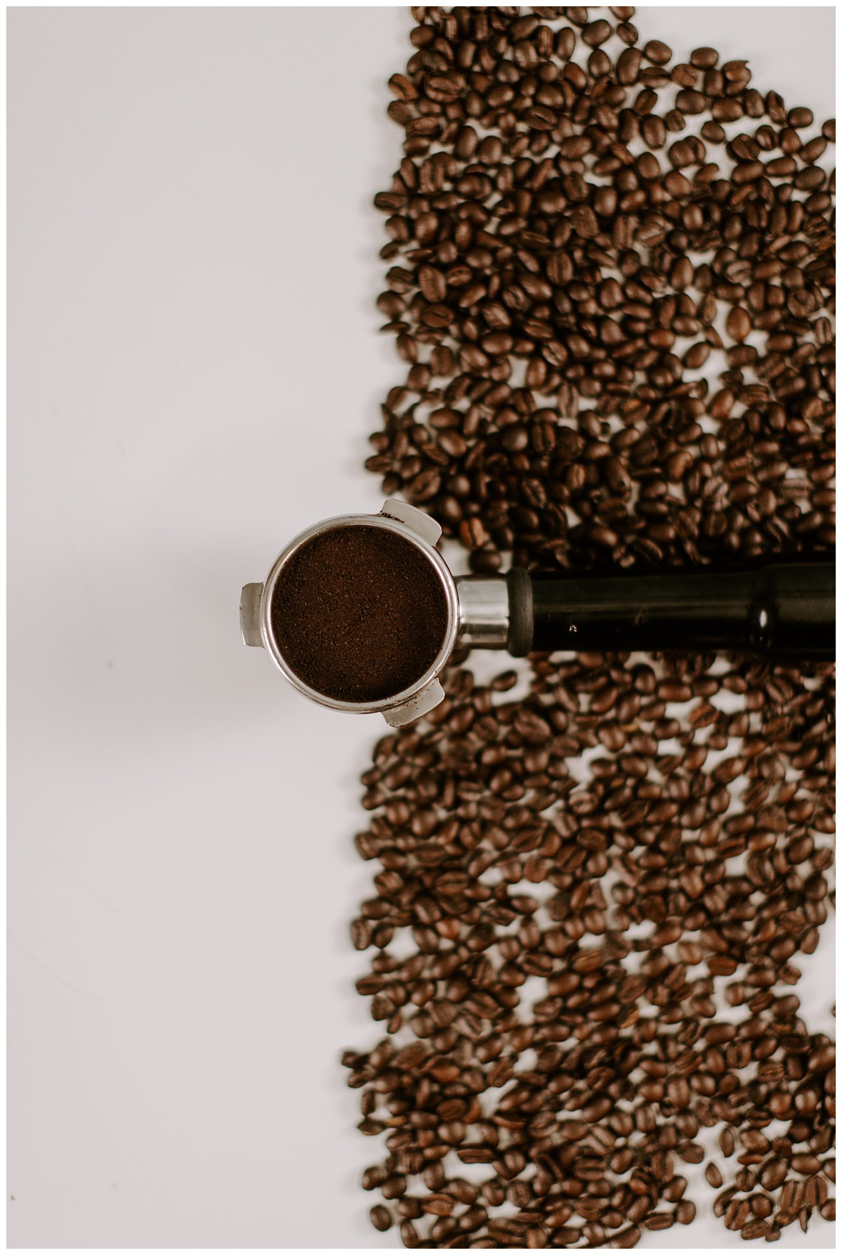 coffee beans and coffee grounds with a port-a filter on a brown table