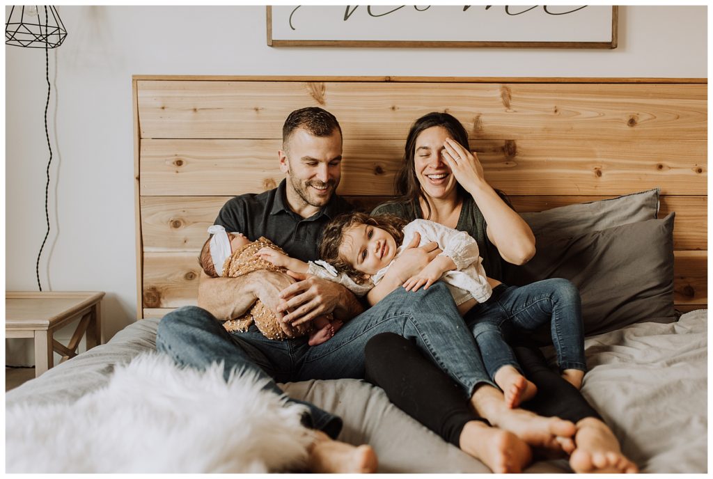 family on bed snuggling newborn