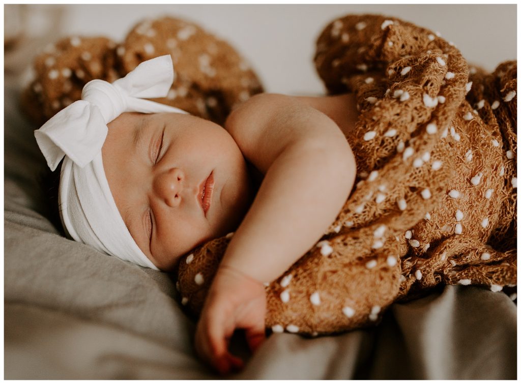 newborn snuggled in a brown blanket